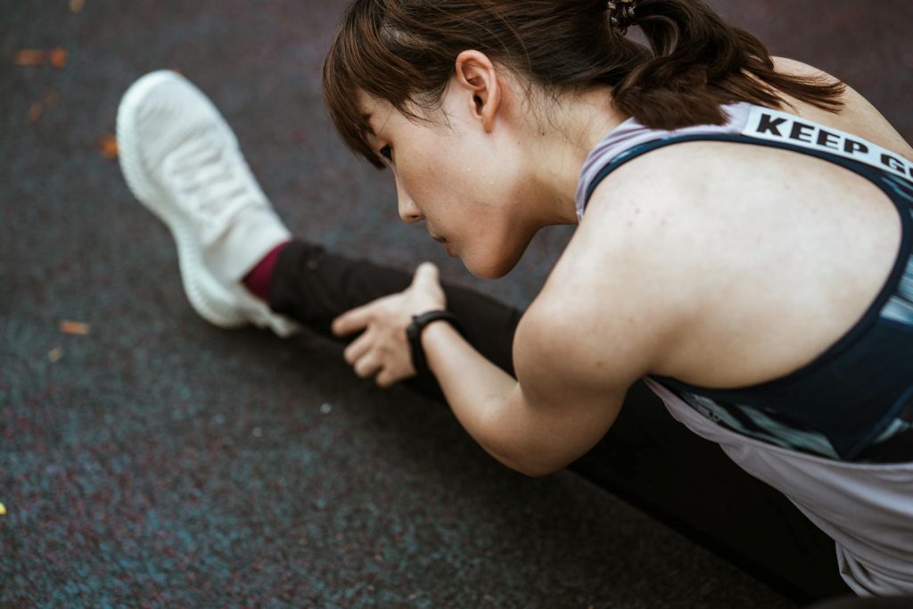 A young woman in sportswear stretching outdoors, emphasizing fitness and wellbeing.