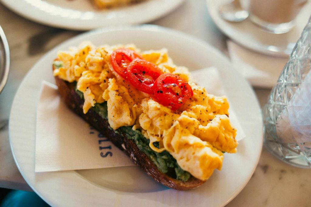 Tasty scrambled eggs on toast with sliced tomatoes, perfect for breakfast or brunch.